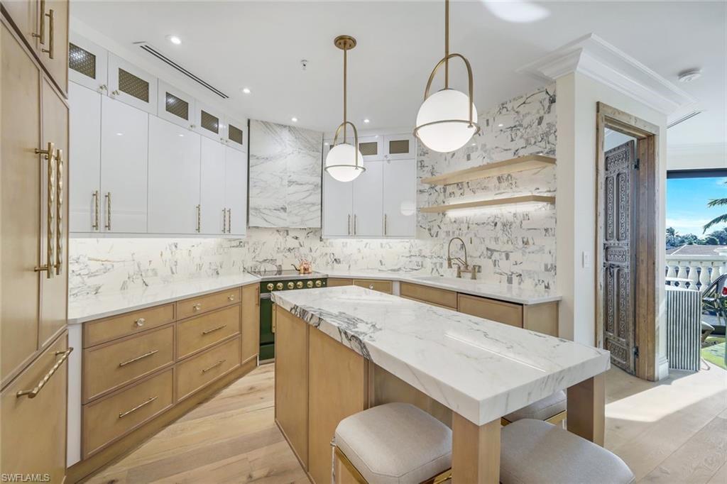Kitchen project with warm wood and white cabinetry, marble-patterned surfaces, a central island and globe pendant lights