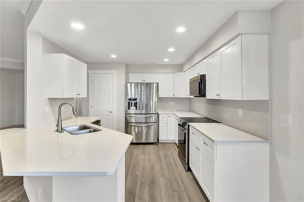 White kitchen with a curved peninsula and stainless steel appliances